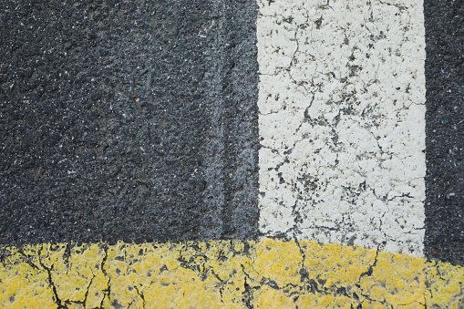 Road with painted traffic lines, Yellow and white lines on the dark gray asphalt, \nhorizontal format for a  background concept.