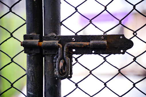 A grungy rusty old latch with A metal wire fence. Retro and Vintage.