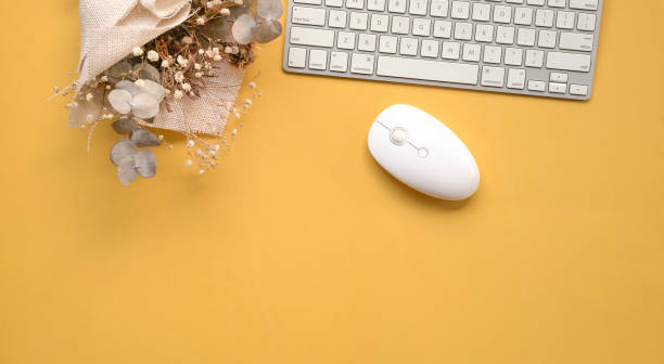 istock Keyboard and mouse with dried flowers as deco on yellow background. 1313230174