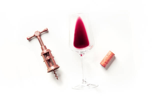 Overhead view of a red wineglass and a wine bottle shot on rustic wooden table. The composition is at the left of an horizontal frame leaving useful copy space for text and/or logo at the right. Predominant colors are brown and red. High resolution 42Mp studio digital capture taken with SONY A7rII and Zeiss Batis 40mm F2.0 CF lens