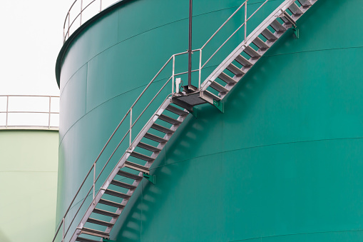 green steel silos with stainless steel ladder and handrail. liquid petroleum metal tanks.