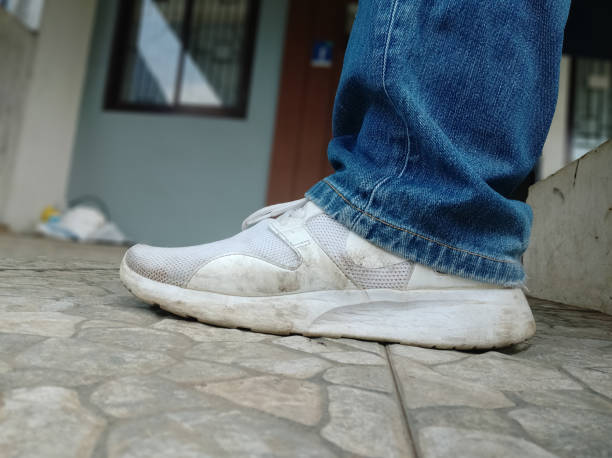 istock Dirty white sneakers and blue jeans 1313233229