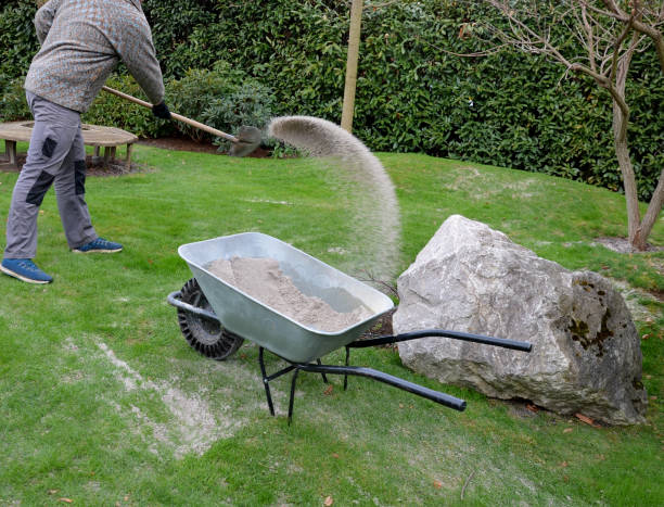 芝生の束を剪定した後、庭師はシリカ白砂を適用します。 - throwing people stone tossing ストックフォトと画像