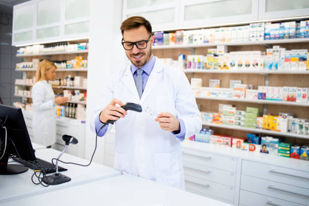 фармацевт держит считыватель штрих-кода в аптечном магазине и продает лекарства. - bar code reader стоковые фото и изображения