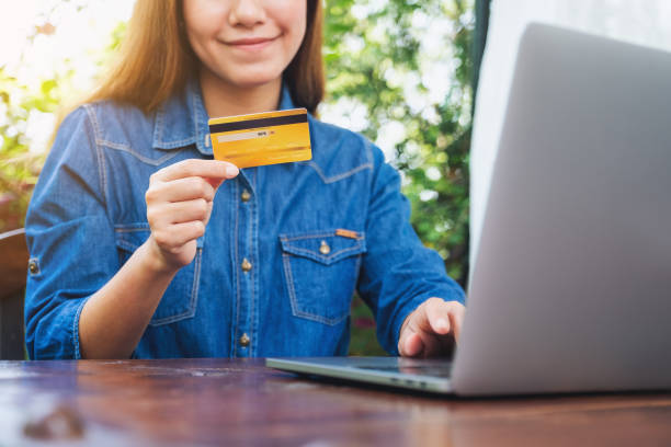 istock a woman holding credit cards while using laptop computer for online shopping 1313236757