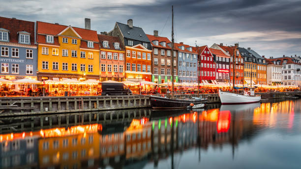 Copenhagen Nyhavn Nightlife Sunset Twilight Panorama Denmark Nightlife Panorama in the famous illuminated Nyhaven District of Copenhagen in moody sunset twilight. Crowds of People walking along the channel to visit Restaurants and Bars in colorful traditional danish houses. Unrecognizable Crowd of People, several cityscape logo signs not in focus. Nyhavn, Copenhagen, Denmark, Nordic Countries, Europe baltic sea people stock pictures, royalty-free photos & images