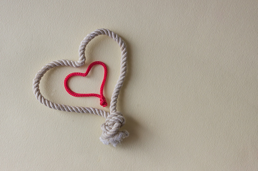 A heart shaped knot made of white and red rope. Love concept.