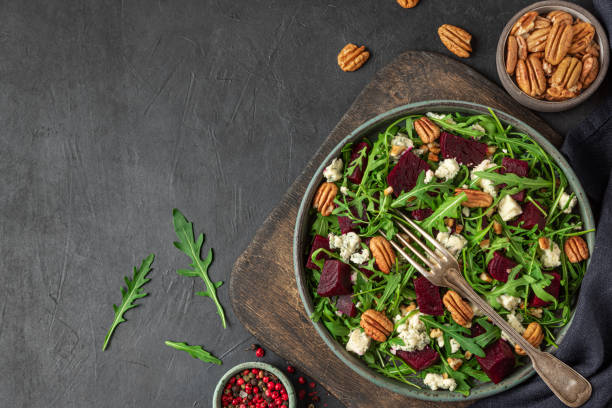 istock Arugula, beet and blue cheese salad with pecan nuts in a plate with fork on black table background. top view 1313241573