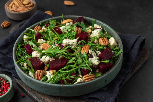 istock Beet or beetroot salad with fresh arugula, blue cheese and pecan nuts in a plate on black background. close up 1313241781