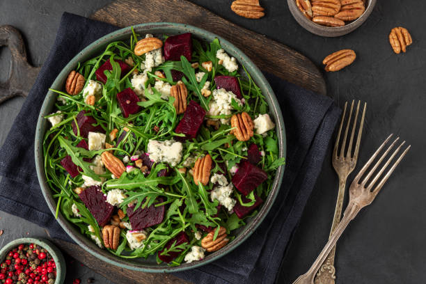 istock Salad with fresh arugula, beetroot, gorgonzola cheese and pecan nuts in a plate with fork on black background. top view. 1313241832