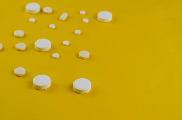 istock Minimalistic composition with random white medical pills on a yellow background. 1313246966