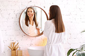 Smiling woman applying cream on face