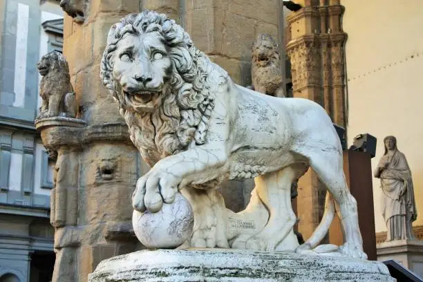 Photo of Florence, Tuscany, Italy: ancient statue of a lion in Piazza della Signoria, sculpture that depicts a lion with a sphere under one paw