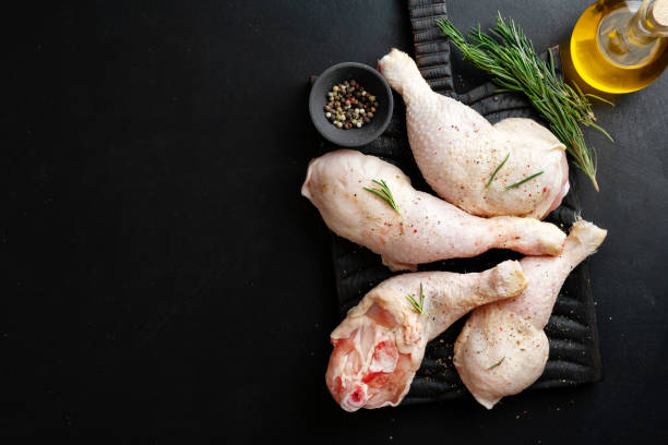istock Raw chicken legs with spices on board on dark background. 1313249694