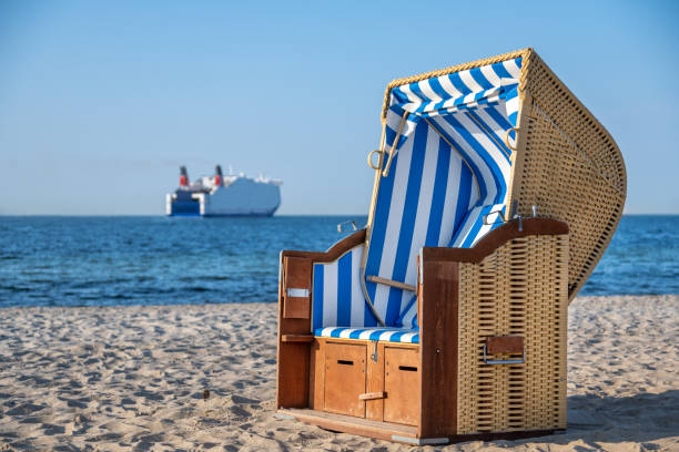 beach chair by the sea, striped blue and white a beautiful beach chair by the sea, striped blue and white. In the background water, blue sky and a ferry, out of focus. hooded beach chair stock pictures, royalty-free photos & images