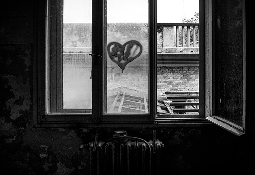 Abandoned hospital window with painted heart, monochrome