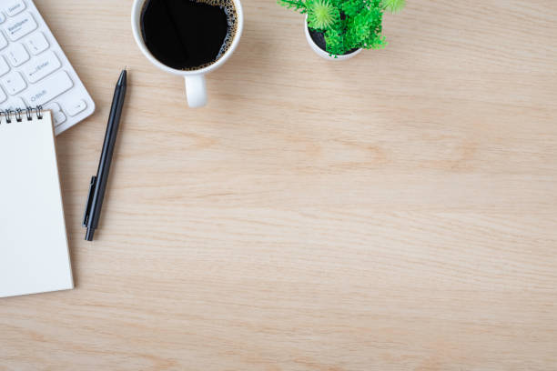istock Top view above of Wood office desk table with keyboard, notebook and notepad, coffee cup with equipment office supplies. Business and finance concept. Workplace, Flat lay with blank copy space. 1313254604