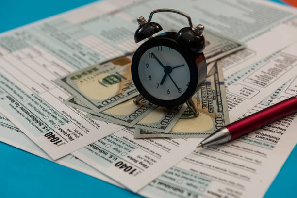 istock tax forms 1040 with clock pen and dollar bills 1313255680