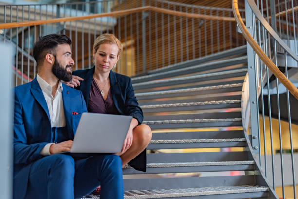 istock Two business people working on staircase using laptop 1313256933