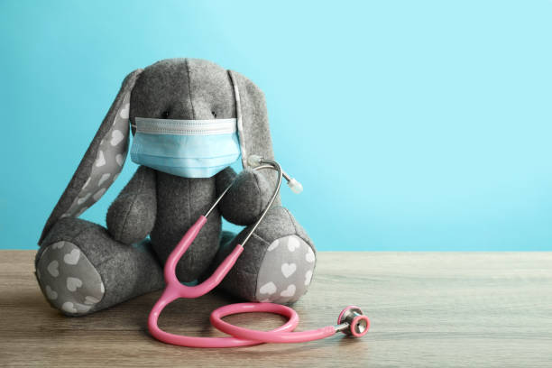 istock Toy bunny with protective mask and stethoscope on wooden table, space for text. Pediatrician practice 1313259902