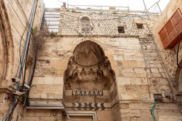 The facade of a residential building decorated with decorative stucco in the Arabian style and suras from the Koran, carved in stone, in the old city of Jerusalem, Israel