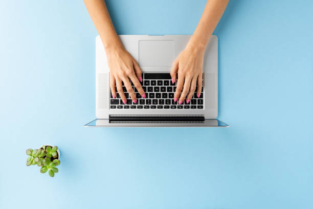istock Woman’s hands using laptop on blue table with copyspace. Business background. Top view 1313264788