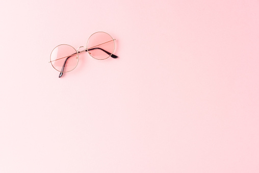 Round sunglasses on pink background. Flat lay
