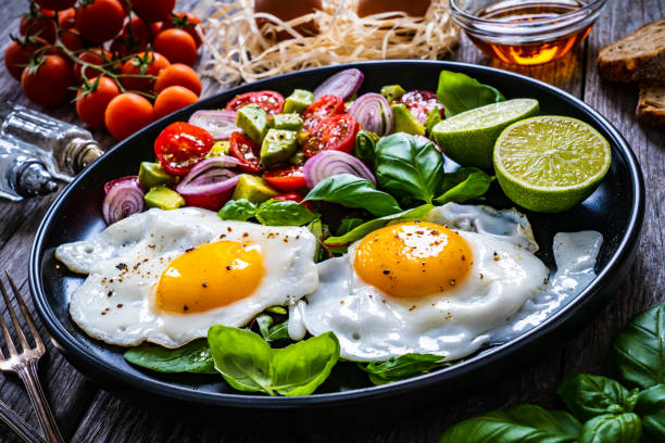 континентальный завтрак - солнечная сторона яйца, белые грибы и греческий салат на деревянном столе - sunny side up стоковые фото и изображения