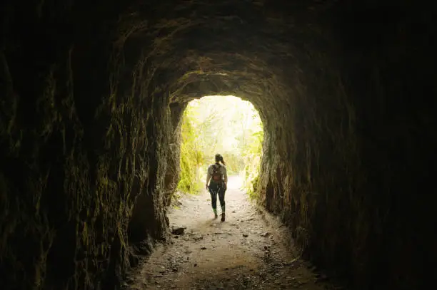 Photo of Young woman walking inside a tunnel in a forest