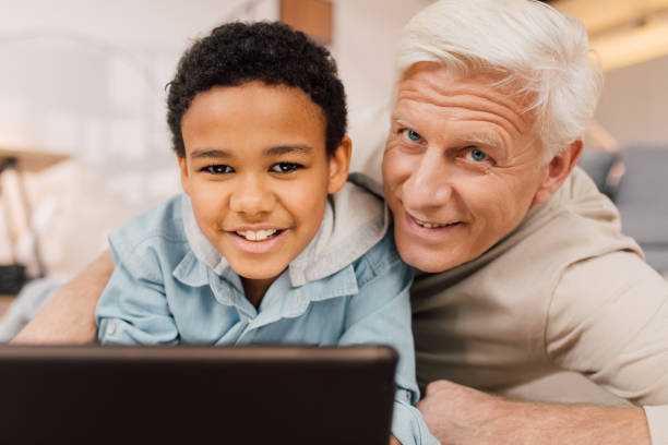 istock Boy laying at the floor and using tablet while relaxing with his grandfather 1313269294