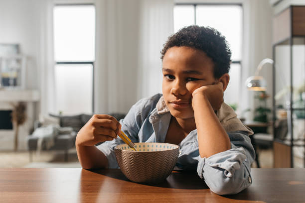 istock Boy looking to the camera while sitting near the empty plate 1313269360
