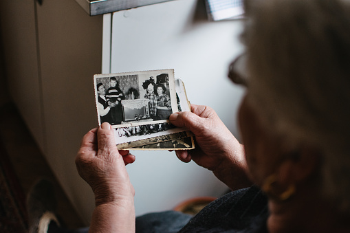 An old lady holding a black and white photograph of her family.