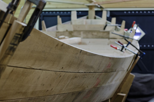 Indoor close-up of an incomplete wooden boat, being handmade - shallow DOF, but one can clearly recognize its shapes