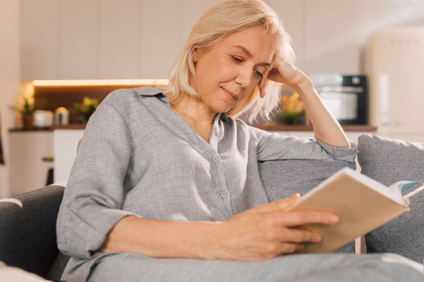 istock Woman sitting at the sofa and reading a book 1313279160