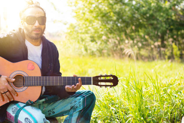 istock Hippy man with beard and glasses playing guitar outdoors on the grass 1313282374