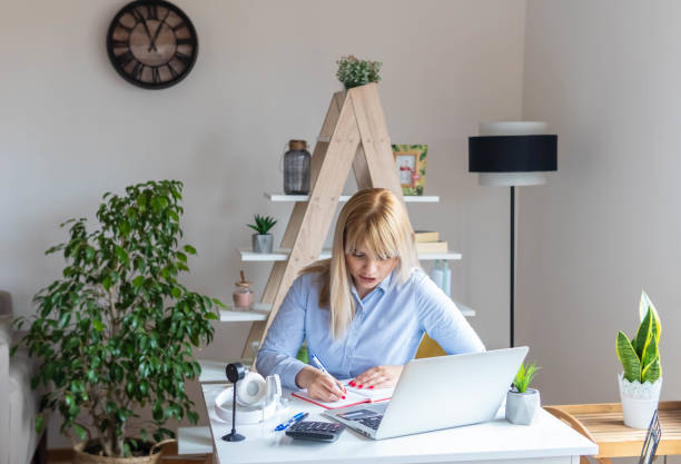 istock Young woman analyzing bills. Beautiful female is using laptop at table while working from home. Home office. 1313282384