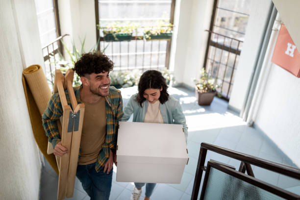 High angle view of a happy Caucasian couple moving into their new apartment High angle view of a young Caucasian couple moving into their new place together, carrying their stuff in, getting ready to reorganize their new apartment, smiling tenant stock pictures, royalty-free photos & images