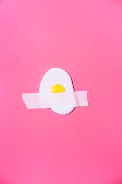 istock Scrambled eggs are glued with white tape to a pink background. Creative fun concept in the style of minimalism. 1313284551