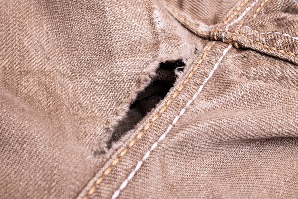 Hole in gray denim close up, background Hole in gray denim close up, background or texture hole in pants stock pictures, royalty-free photos & images