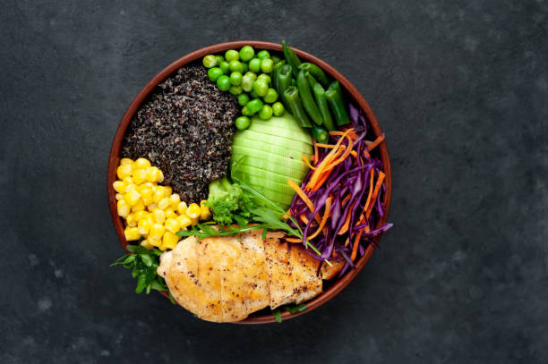 istock Bowl Buddha. Quinoa, chicken breast, avocado, red cabbage, arugula, carrot, green peas, corn, broccoli, green beans in a plate on a stone background, with copy space for your text 1313287148