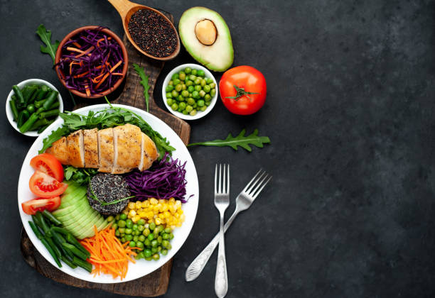 istock Bowl Buddha . Quinoa, chicken breast, arugula, avocado, red cabbage, carrot, green peas, corn, tomato, green beans in a white plate on a stone background. 1313287198