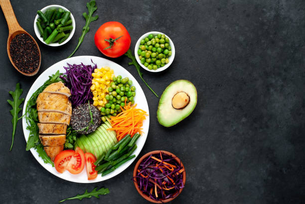 istock Bowl Buddha. Quinoa, chicken breast, arugula, avocado, red cabbage, carrot, green peas, corn, tomato, green beans in a white plate on a stone background. with copy space for your text 1313287279