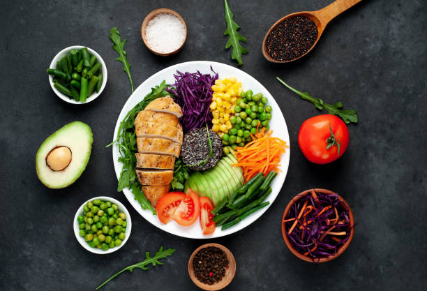 istock Bowl Buddha . Quinoa, chicken breast, arugula, avocado, red cabbage, carrot, green peas, corn, tomato, green beans in a white plate on a stone background. 1313287306