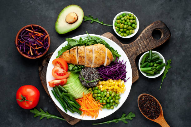 istock Bowl Buddha . Quinoa, chicken breast, arugula, avocado, red cabbage, carrot, green peas, corn, tomato, green beans in a white plate on a stone background. 1313287322