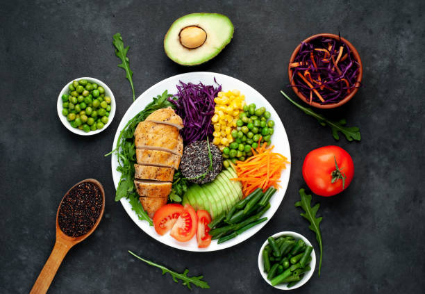istock Bowl Buddha . Quinoa, chicken breast, arugula, avocado, red cabbage, carrot, green peas, corn, tomato, green beans in a white plate on a stone background. 1313287330