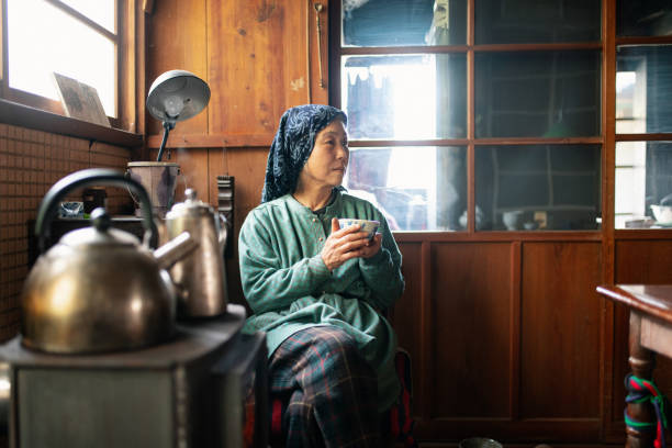 Senior woman relaxing drinking tea in her kitchen. Kamikatsu, Japan