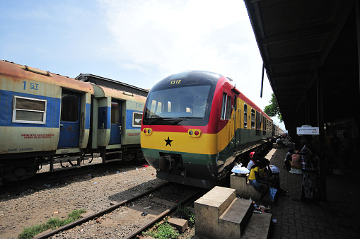 Accra, Ghana: Accra Train Station, start of the line to Kumasi - Ghana Railways train in the colours of the Ghanaian flag, people in the platform.