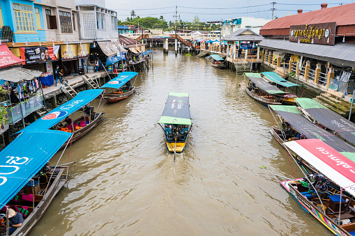 Samut Songkhram, Thailand - April, 04, 2021: Tourists shopping and boat ride around in Amphawa floating market. It is one of the most popular floating markets in Thailand.Many tourists come to travel much less due to the coronavirus outbreak.