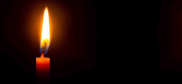 istock Close up single candle light and flame on black background 1313291497