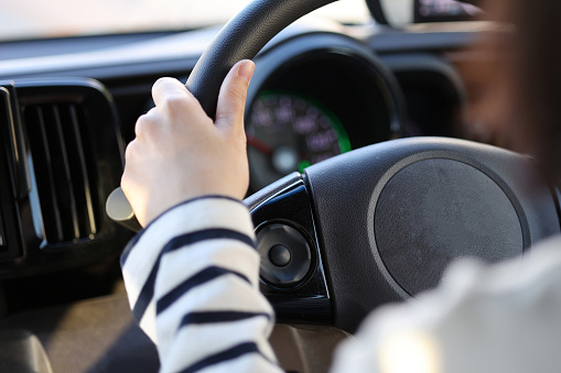 Woman's hand holding the steering wheel while driving a car